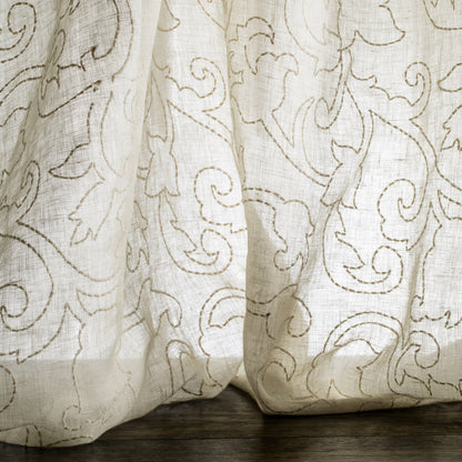 Sheer curtain with intricate floral pattern on a wooden surface