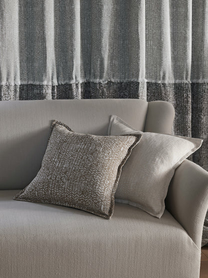 Gray sofa with textured pillows against a striped curtain background