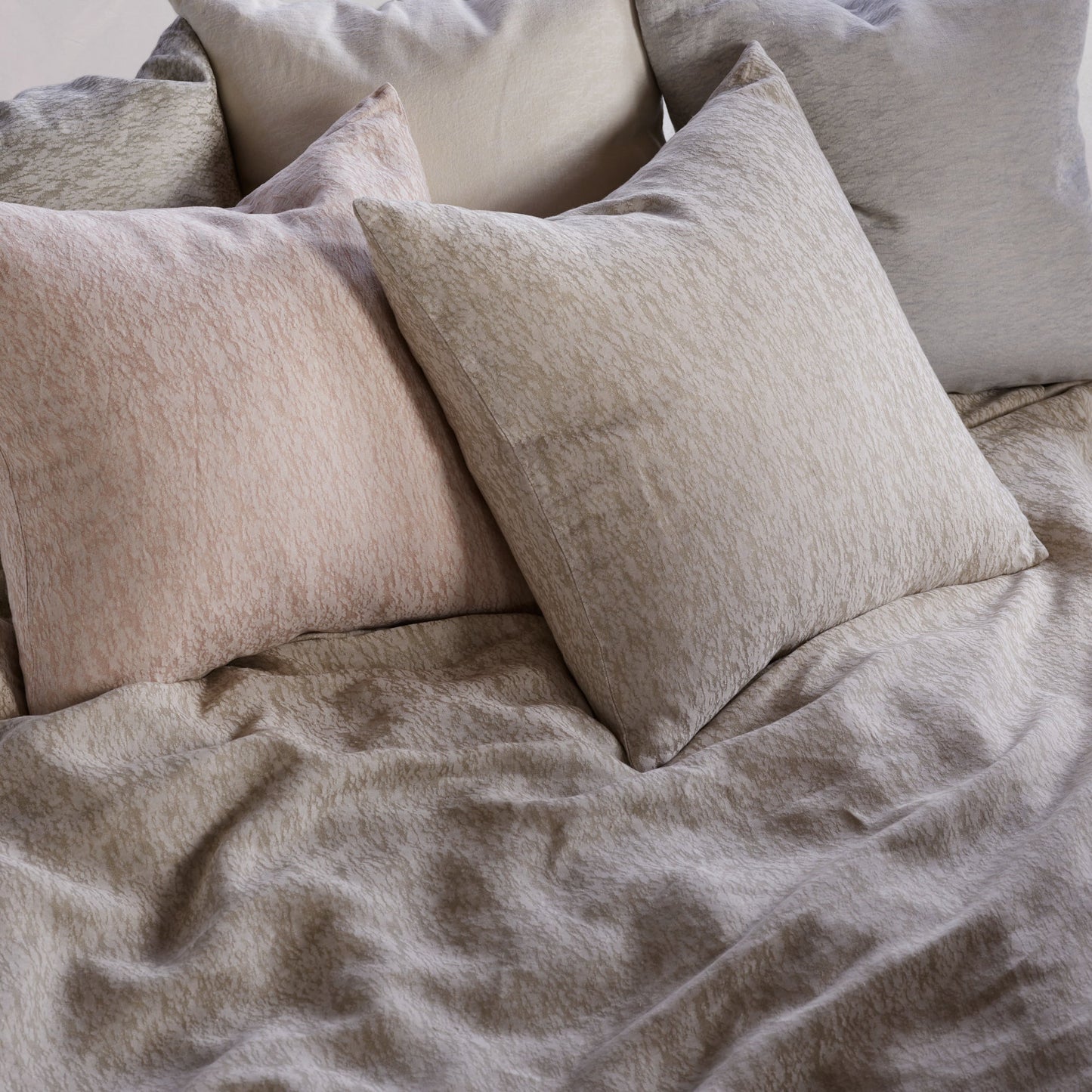 Neatly arranged pillows on a bed with beige bedding