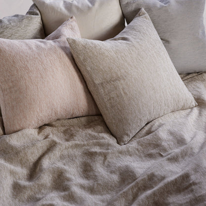 Neatly arranged pillows on a bed with beige bedding